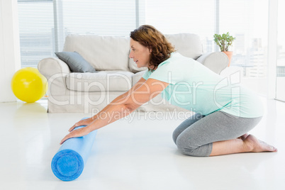 Full length of mature woman rolling exercise mat