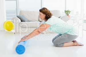 Full length of mature woman rolling exercise mat