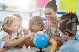 Teacher looking at schoolchildren touching globe