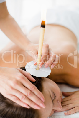 Masseur giving ear candle treatmet to woman