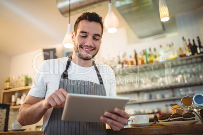 Happy barista using digital tablet at cafe