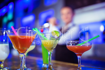 Cocktail glasses on counter with bartender in background