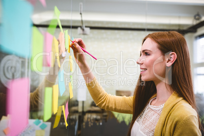 Happy businesswoman writing on sticky notes