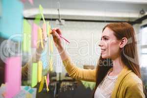 Happy businesswoman writing on sticky notes