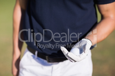 Midsection of man holding golf ball