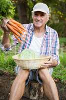 Portrait of man with carrots and cabbage at garden