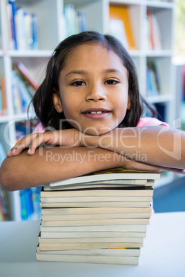 Girl leaning on books at table in school library