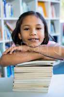 Girl leaning on books at table in school library