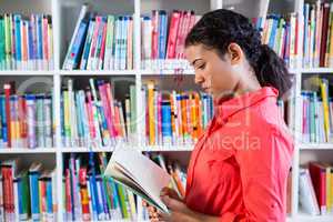 Teacher reading book at library in school
