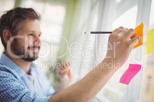Businessman writing on adhesive notes at creative office