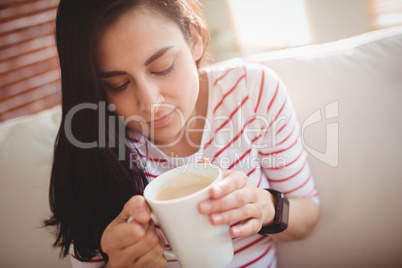 Woman holding coffee cup on couch