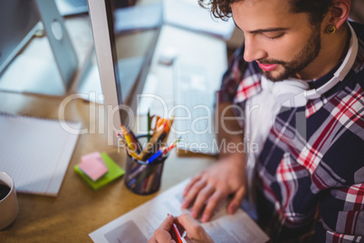 Creative businessman writing on paper at computer desk