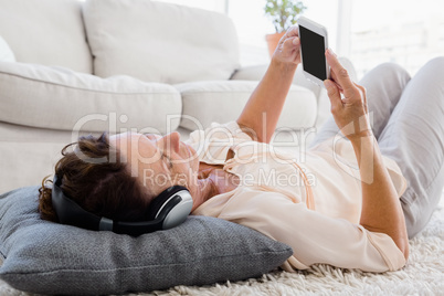 Mature woman using phone while listening to headphones