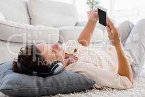 Mature woman using phone while listening to headphones