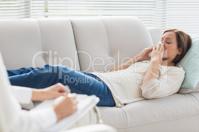 Woman lying on sofa by therapist