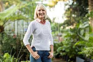 Confident mature woman standing at greenhouse