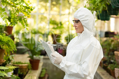 Female scientist wearing clean suit writing in clipboard