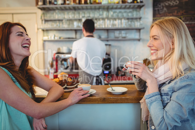 Cheerful customers talking at counter in coffee shop