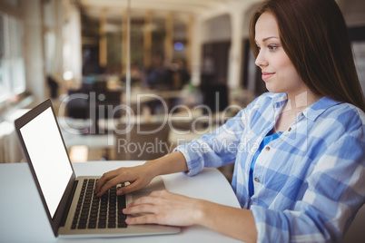 Young businesswoman working on laptop in creative office