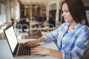 Young businesswoman working on laptop in creative office