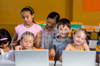 Smiling children using laptops