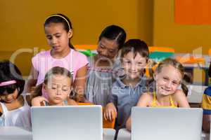 Smiling children using laptops
