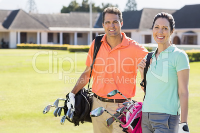 Portrait of couple carrying golf bags