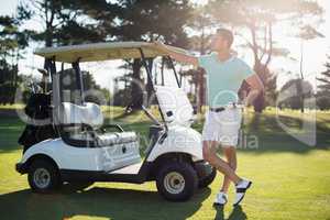 Full length of man by golf buggy