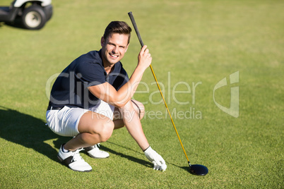 Portrait of happy man placing golf ball on tee