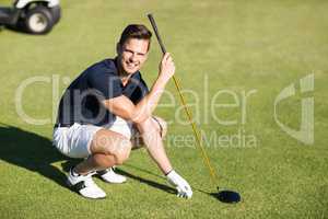 Portrait of happy man placing golf ball on tee