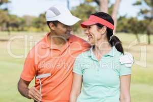 Smiling golfer couple with arm around