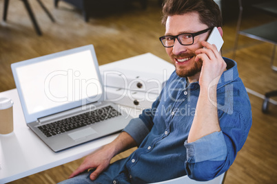 Portrait of happy executive talking on cellphone at creative off