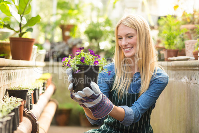 Female gardener smiling while holding flowering plant