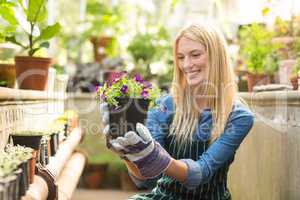 Female gardener smiling while holding flowering plant
