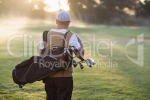 Rear view of man carrying golf bag