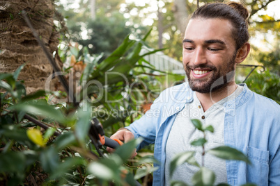 Happy confident gardener using hedge clippers at garden