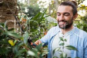 Happy confident gardener using hedge clippers at garden