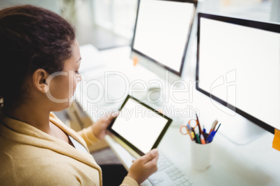 Businesswoman using digital tablet at desk in creative office