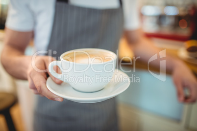 Midsection of barista serving coffee at shop