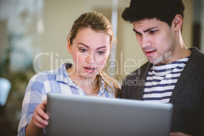 Surprised executives looking at laptop in creative office