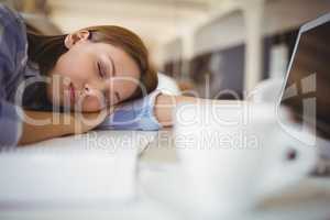 Tired businesswoman taking nap on desk in creative office