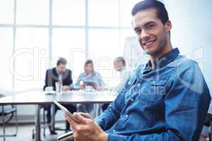 Businessman using digital tablet against colleagues in meeting r