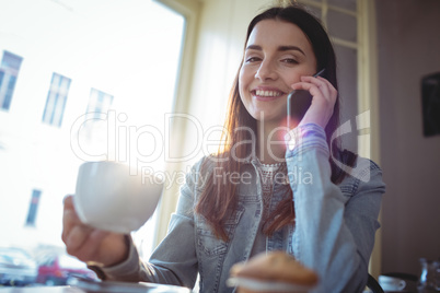 Portrait of happy woman listening to cellphone at cafe