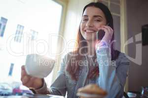 Portrait of happy woman listening to cellphone at cafe