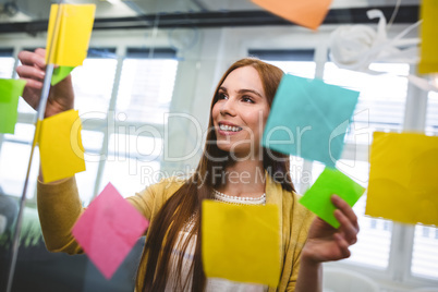 Businesswoman attaching sticky notes on glass