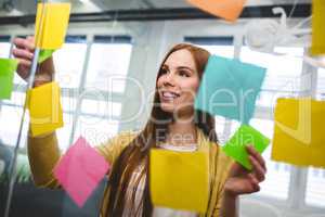 Businesswoman attaching sticky notes on glass