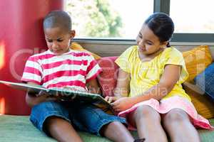 Front view of siblings reading book at home