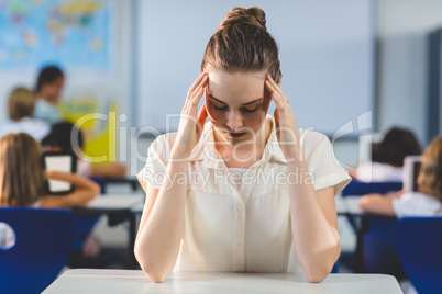 Depressed female teacher touching her head