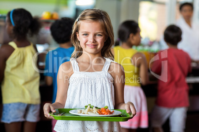 Schoolgirl holding tray in canteen