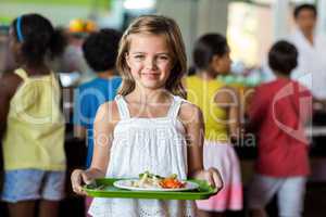 Schoolgirl holding tray in canteen